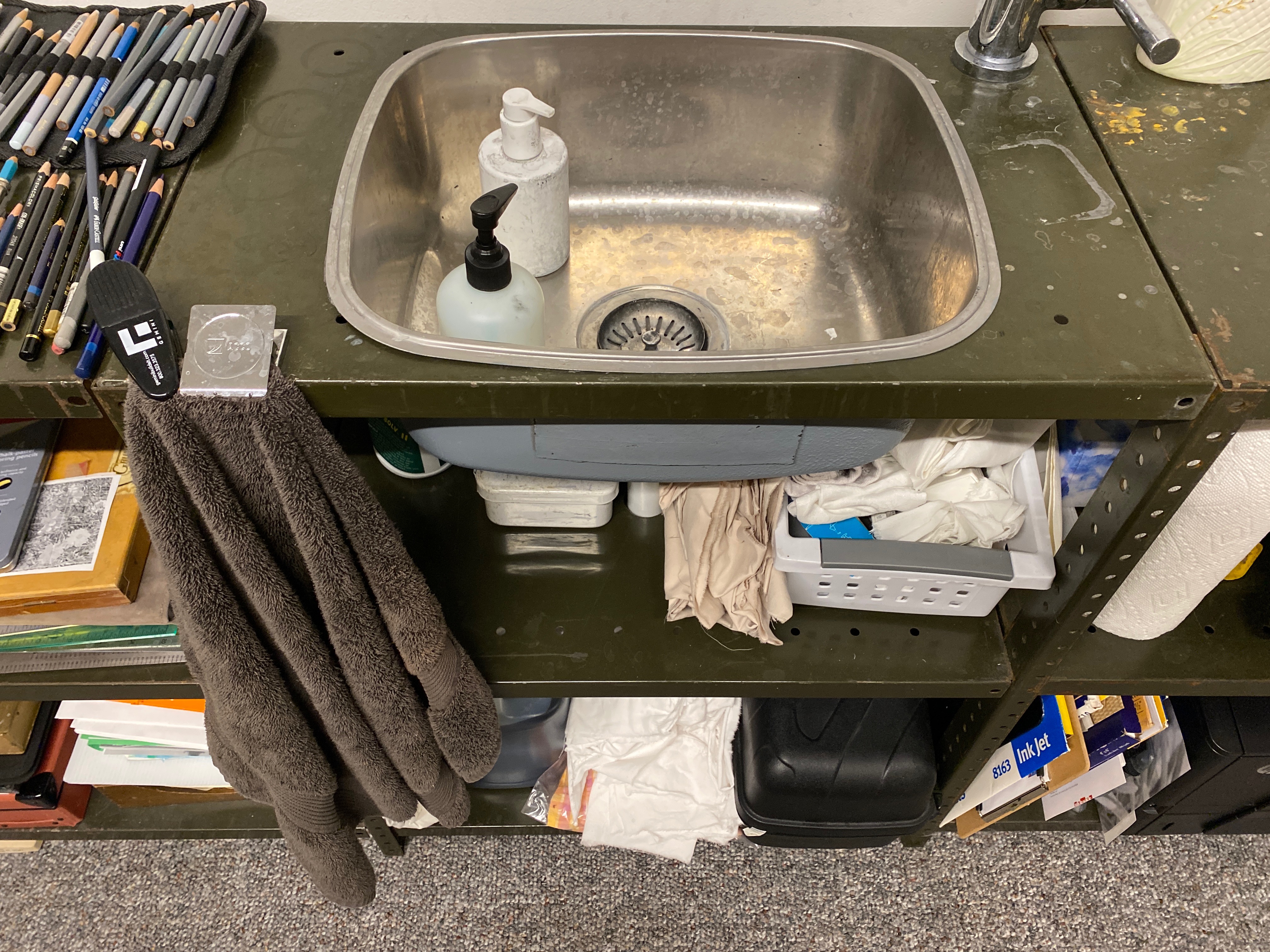 metal sink is sunk into a row of metal shelves